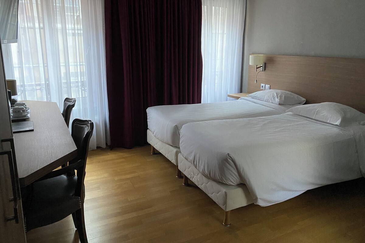 Ein Hotelzimmer mit zwei Betten, einem Schreibtisch und einem Stuhl.