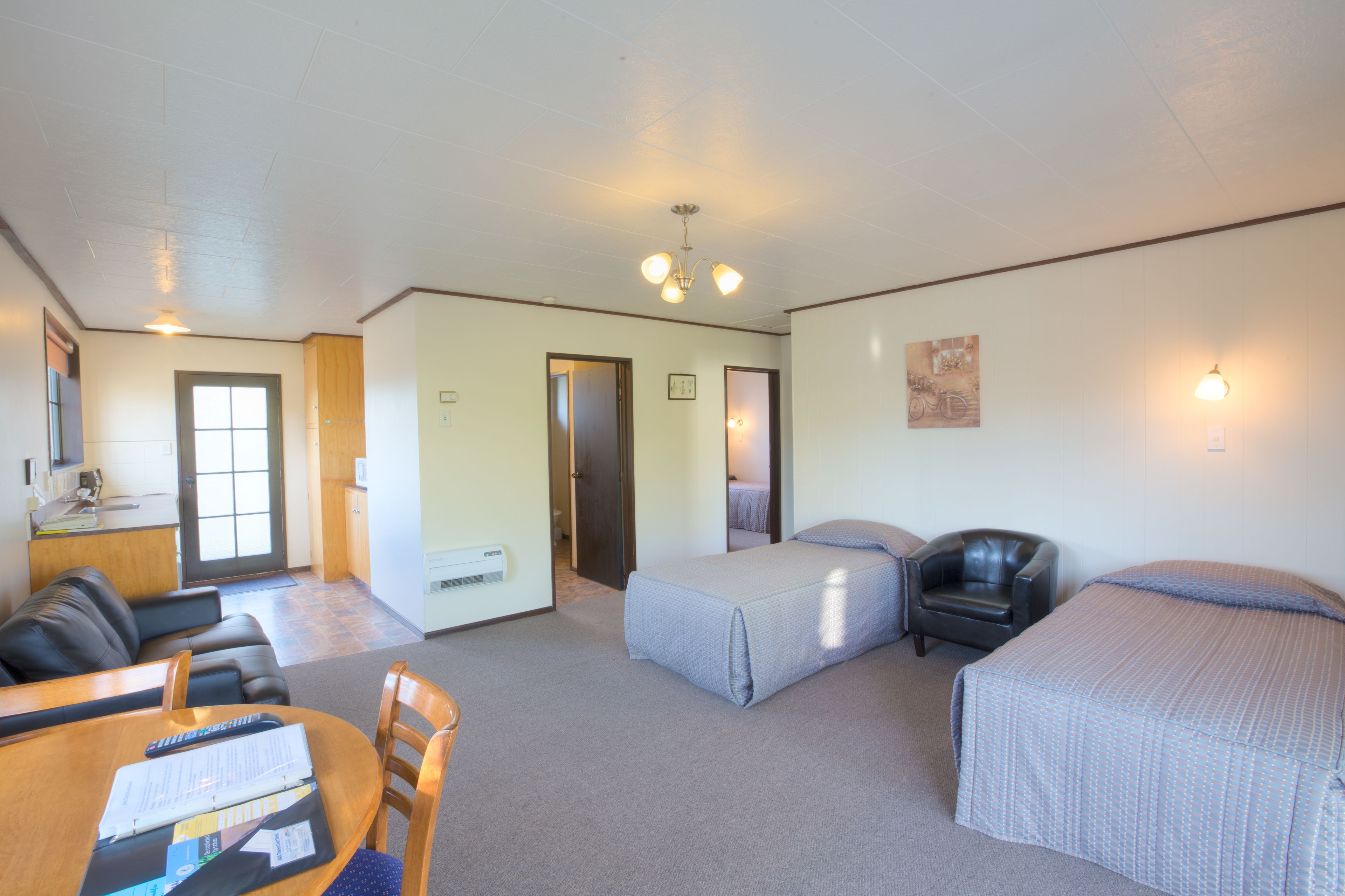 A room with a bed, a chair, a desk, and a dining table.