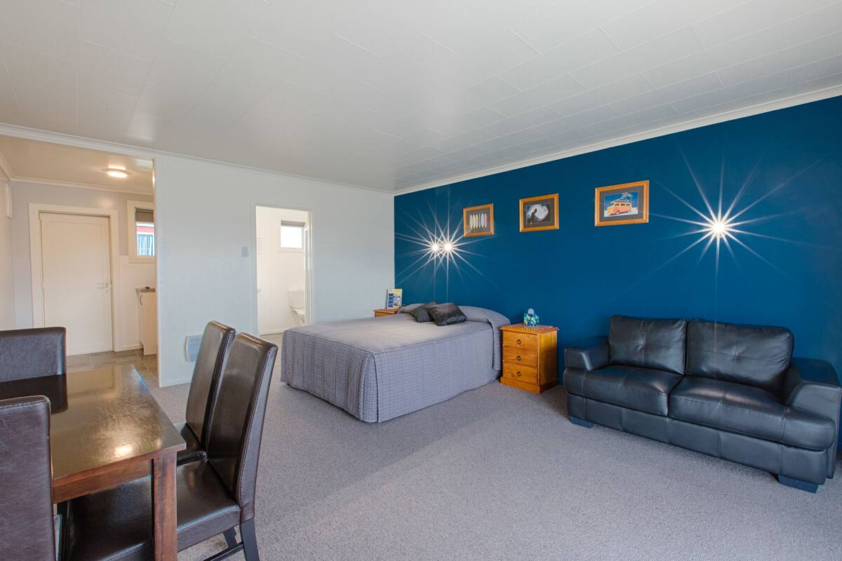 A bedroom with a bed, a dresser, a desk, and a couch.
