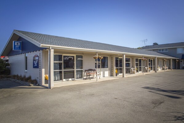A hotel with a covered entrance, large windows, and outdoor seating.