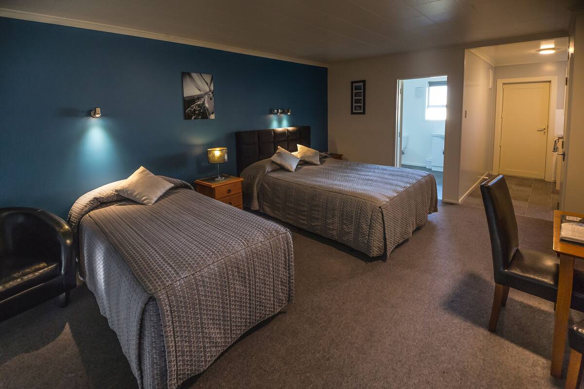 A bedroom with two beds, a desk, and a chair.