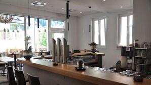 Un área de bar moderna con mostrador de madera, taburetes y una máquina de café.