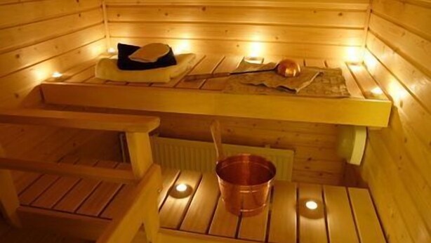 Una sauna de madera con bancos y un cubo de cobre.