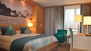 Una habitación de hotel con una cama grande, un escritorio, una silla y una ventana con cortinas.