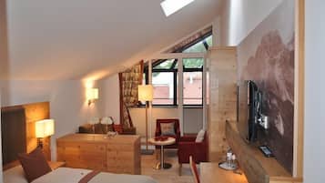 Quarto de hotel com cama, escrivaninha, cadeira, mesa e televisão.