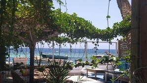 Un espace de détente aménagé au bord de la plage, avec des sièges en plein air et une vue sur l’océan.