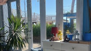 Une pièce baignée de lumière, avec une table de billard, un banc rembourré et un meuble contenant des objets décoratifs.