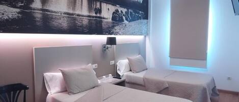 Habitación de hotel con dos camas, una obra de arte grande en la pared, un escritorio y una silla.
