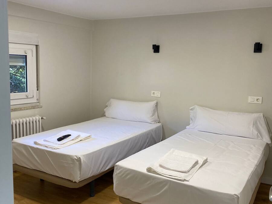 Una habitación con dos camas individuales, una ventana con vistas, un radiador y una lámpara en el techo.