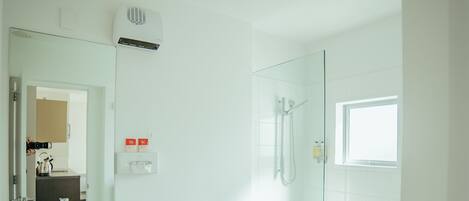 Un baño moderno con lavamanos blanco, inodoro y ducha con mampara de vidrio.