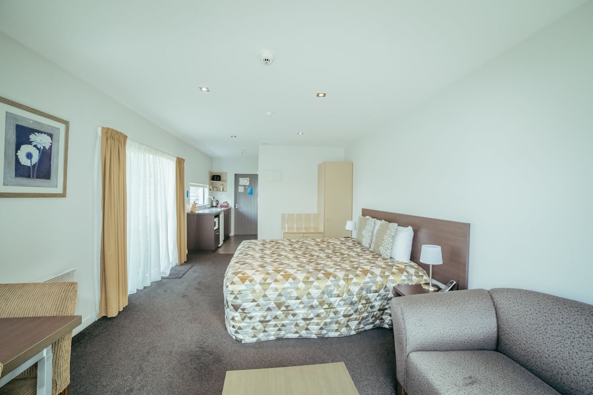 Une chambre d’hôtel avec un grand lit, un canapé, un bureau et une salle de bain visible au fond.