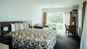 Hotellihuone, jossa on suuri sänky, työpöytä, tuoli ja näkymä ulos.