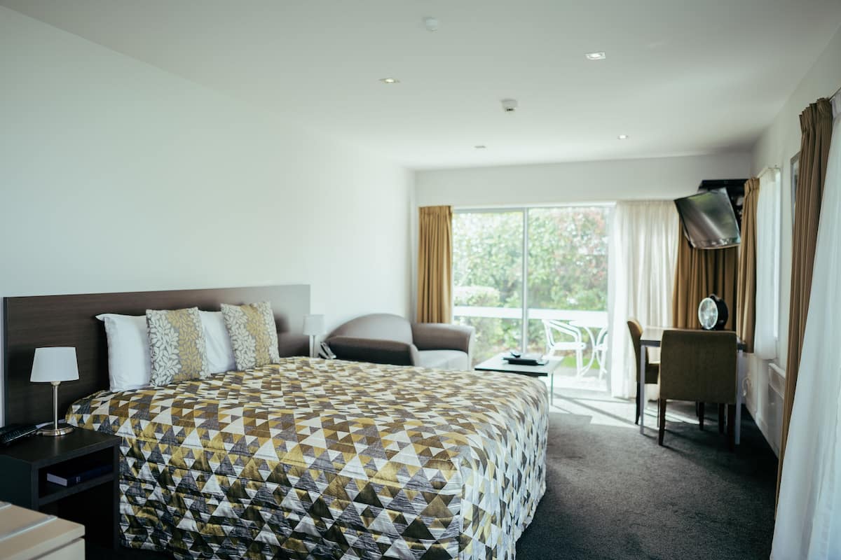 Une chambre d’hôtel avec un grand lit, un bureau, une chaise et une vue sur l’extérieur.