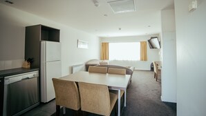 Kompakti hotellihuone, jossa on pieni keittiö, ruokailutila ja televisio.