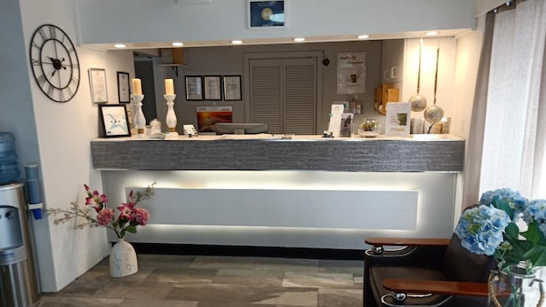 Un espace d’accueil comprenant un comptoir, des tableaux encadrés, une horloge et un vase avec des fleurs.