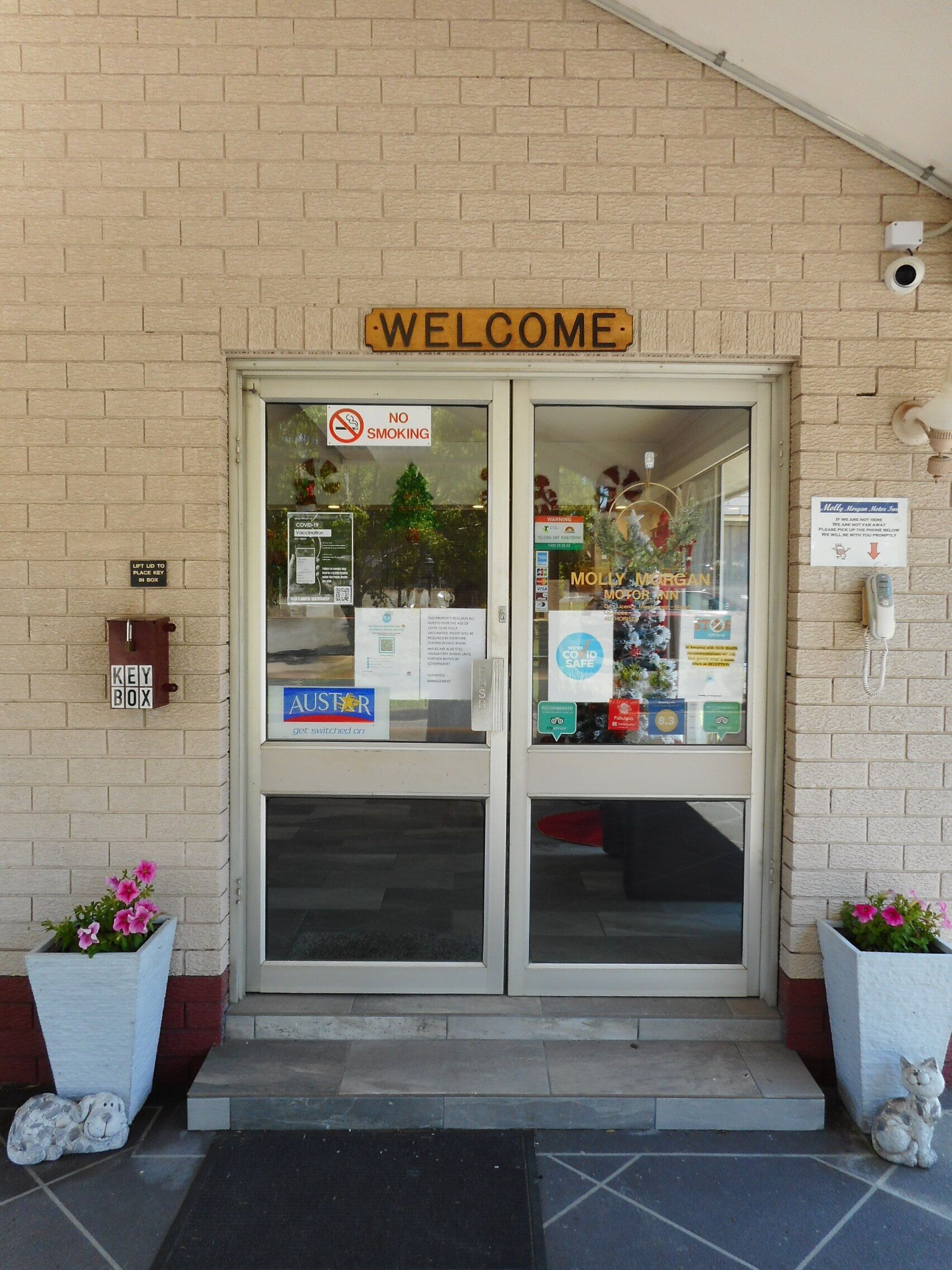 A hotel entrance with a 'WELCOME' sign, a 'NO SMOKING' sign, a key box, and a 'Molly Morgan' sign.