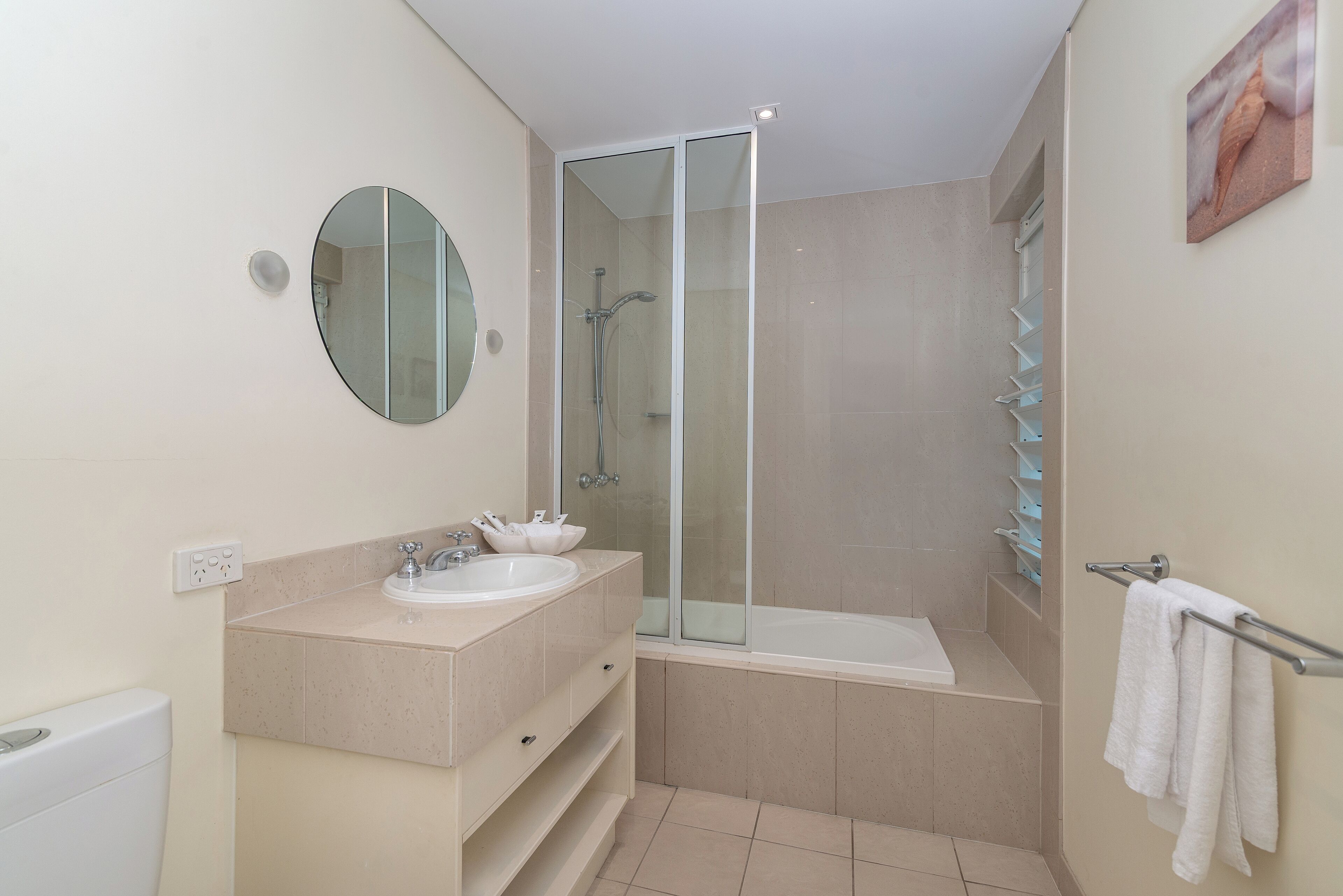 A modern bathroom with a glass-enclosed shower, a bathtub, and a vanity with a sink and mirror.