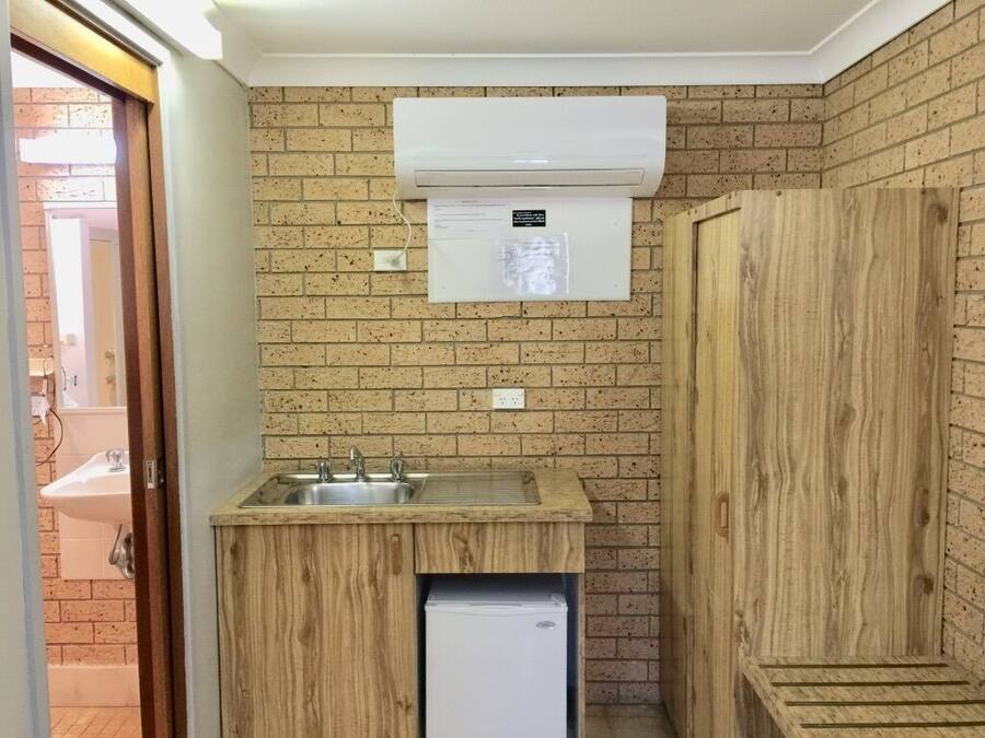 Cocina compacta con lavamanos, un refrigerador pequeño y aire acondicionado integrado.