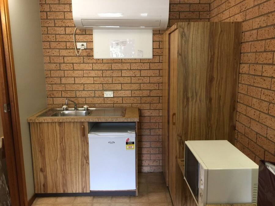 Una cocina compacta con refrigerador integrado, microondas y pileta.