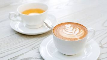 Twee witte koffiekopjes op een witte marmeren tafel.