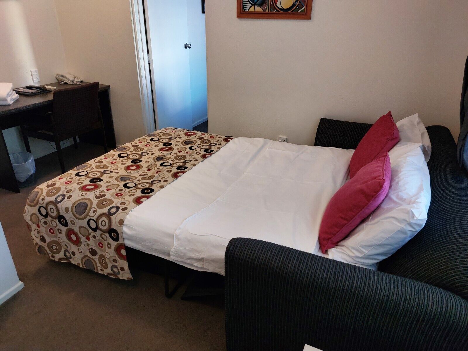 A hotel room with a bed, a desk, and a chair.