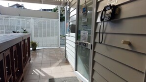 A reception area with a 'Welcome' mat, a reception desk, a phone, and a CCTV sign. - Eden Park Motel (Auckland)