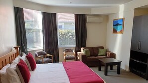 A hotel room with a bed, a sofa, a TV, and a window with curtains. - Eden Park Motel (Auckland)