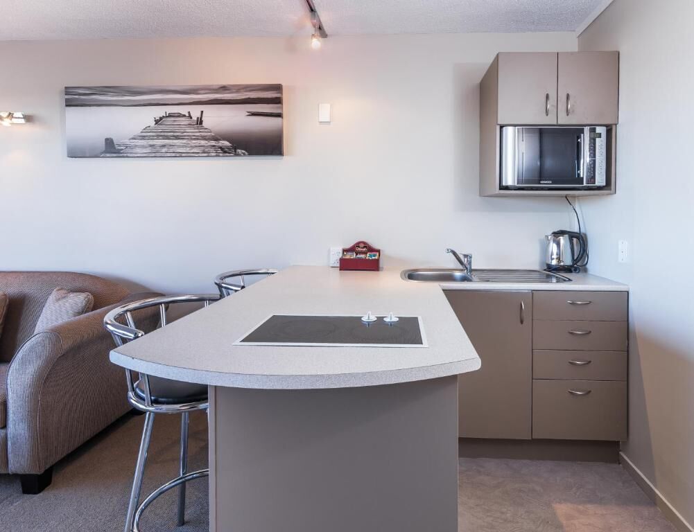A compact kitchen with a microwave, a sink, and a small island with stools.
