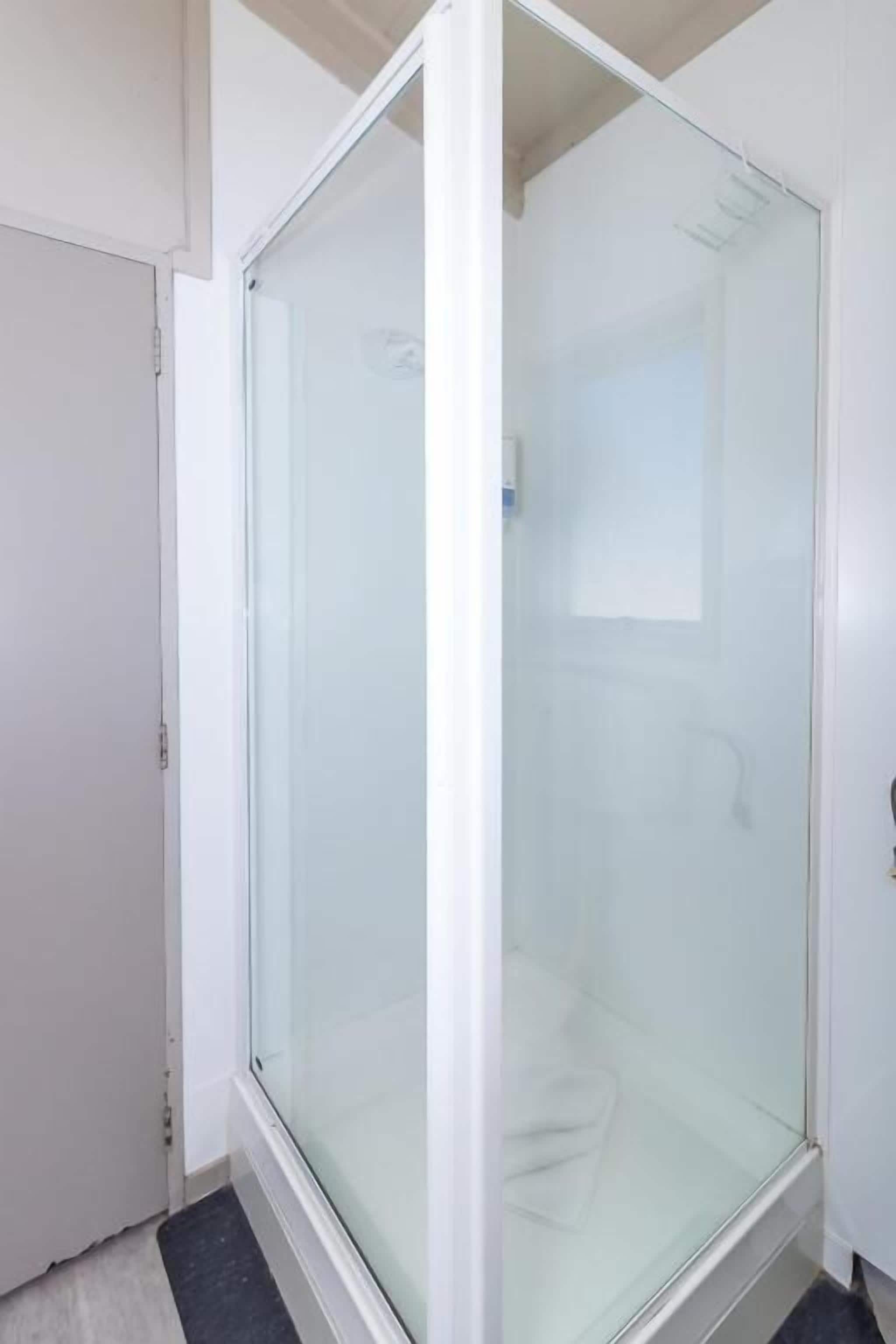 A glass-enclosed shower area with a white door and a small window.