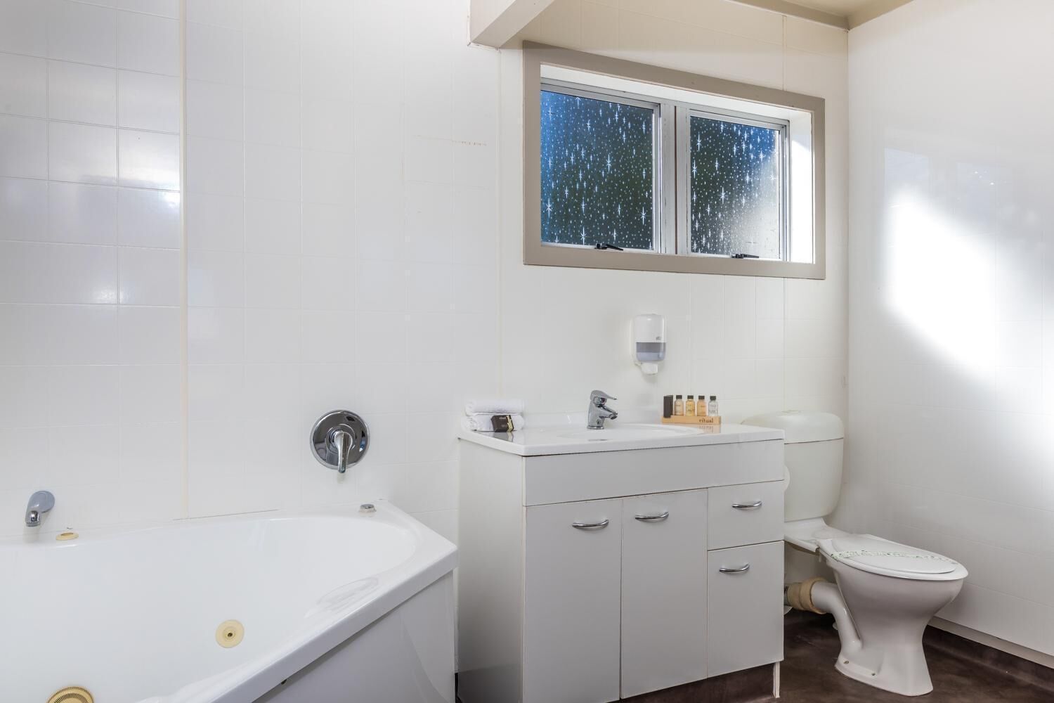 A modern bathroom with a bathtub, toilet, and vanity.
