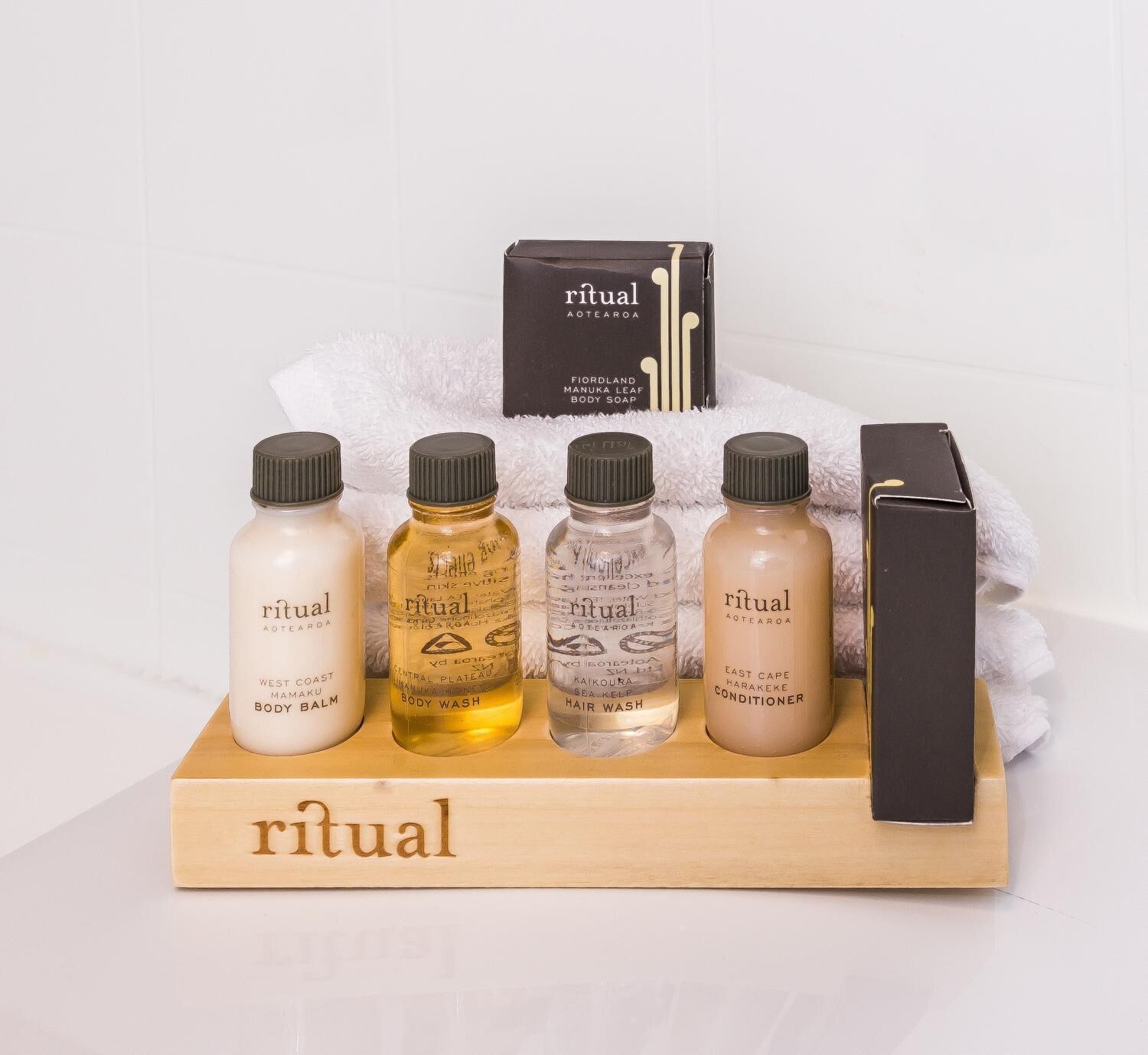 A wooden tray with five bottles of Ritual body care products and a black box.
