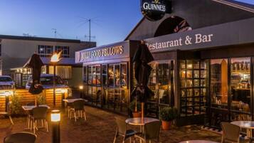An outdoor seating area with tables and chairs, a restaurant and bar sign, and a Guinness sign.
