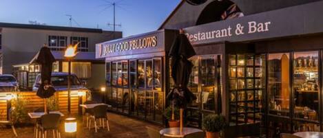 An outdoor seating area with tables and chairs, a restaurant and bar sign, and a Guinness sign.