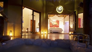 A room with a bed, a large mirror, and a stone seating area. - Pondoro Game Lodge  - Open to Kruger Park (Hoedspruit)