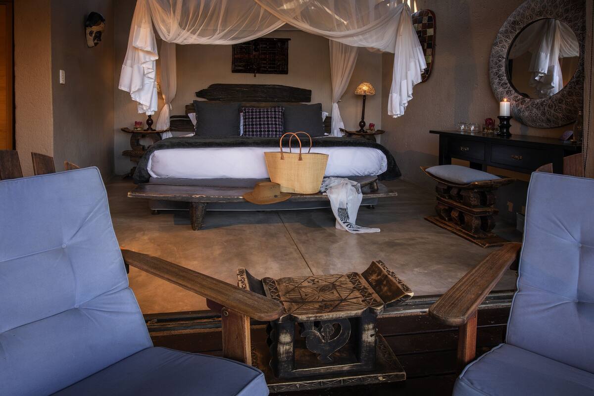 A bedroom with a bed, bedside tables, a mirror, and a chair.