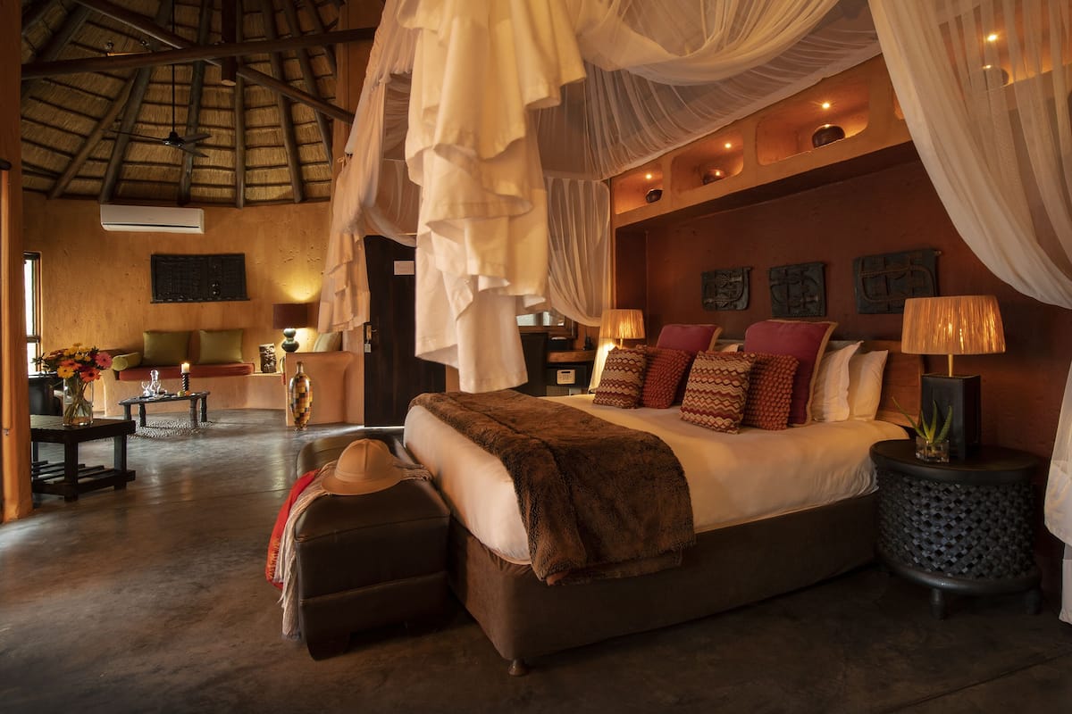 A spacious bedroom with a large bed, a sitting area, and a dining area.
