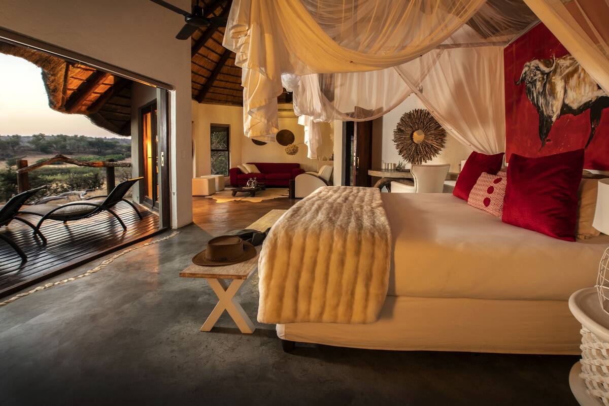 A spacious bedroom with a large bed, a red sofa, and a view of the outdoors.