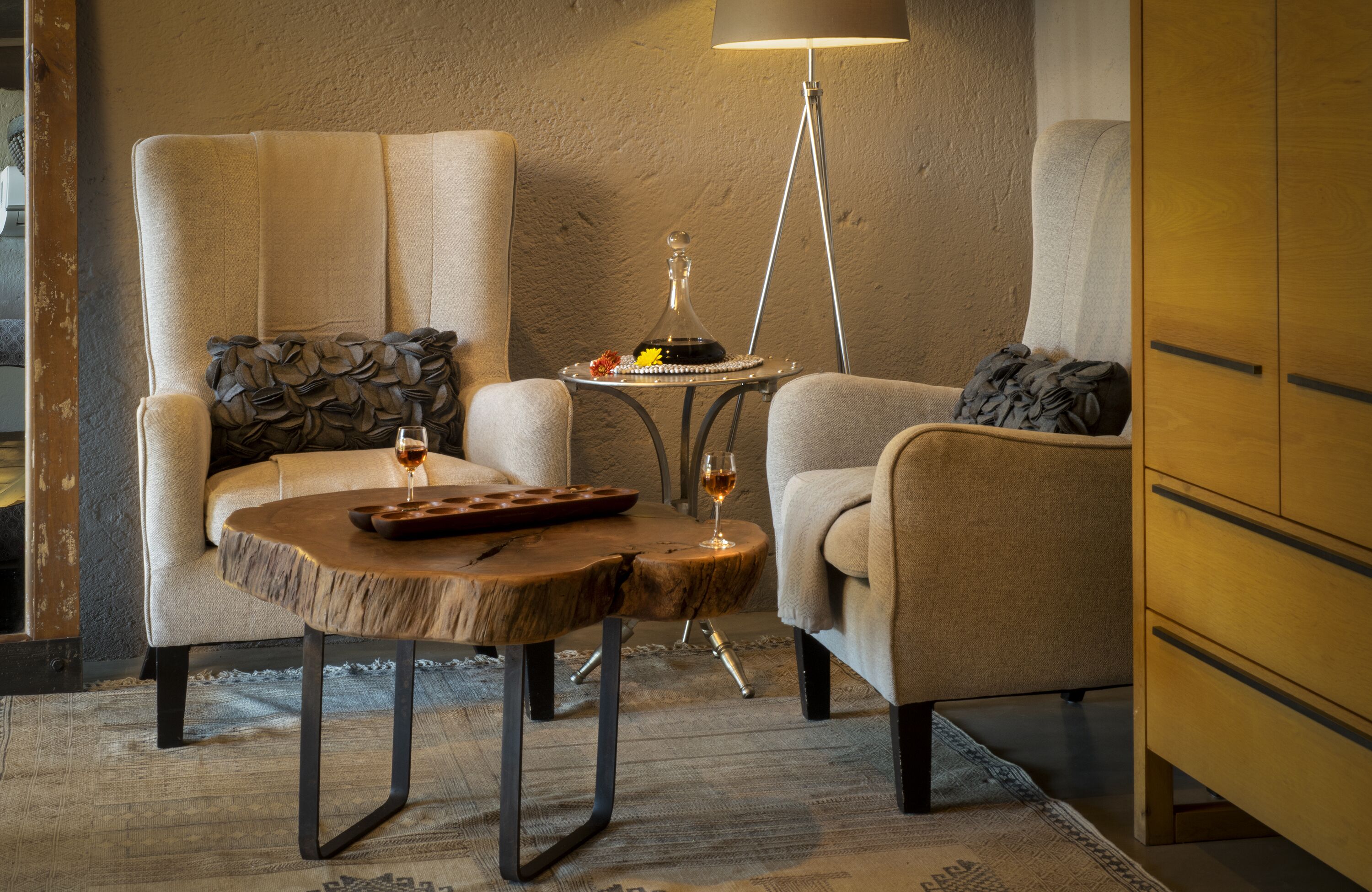 A cozy room with two armchairs, a small wooden table with a tray and a wine glass, and a floor lamp.