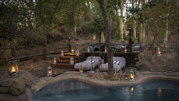 A hot tub surrounded by stone walls, wooden deck, and benches. - Pondoro Game Lodge  - Open to Kruger Park (Hoedspruit)