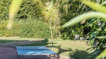 Mesa de tenis de mesa en un parque con árboles y césped alrededor.