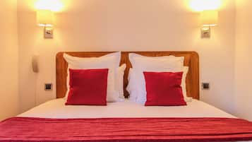 A bed with white bedding, two red pillows, and a wooden headboard.