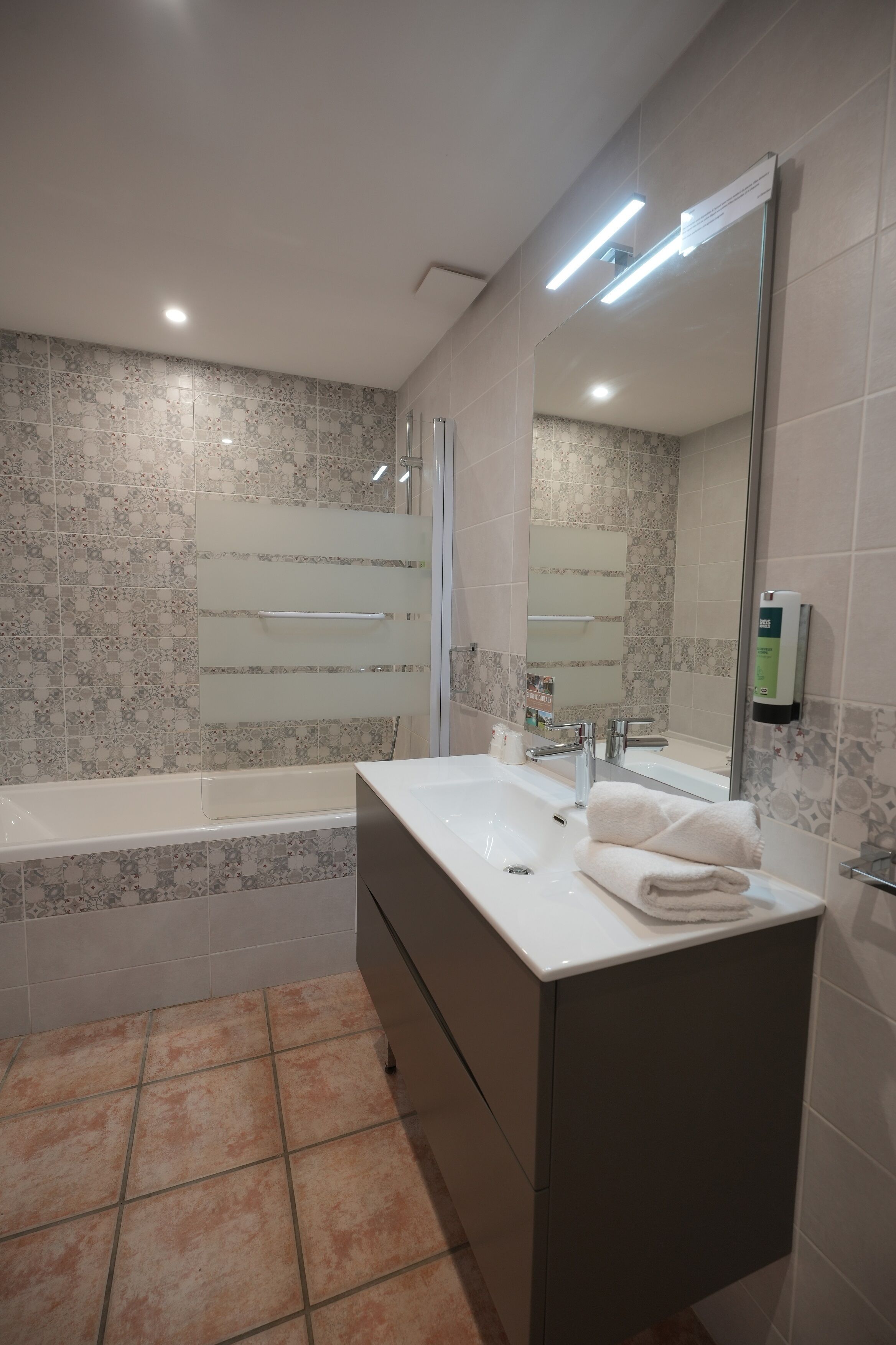 Un baño moderno con bañera, tocador con espejo y zona de ducha.