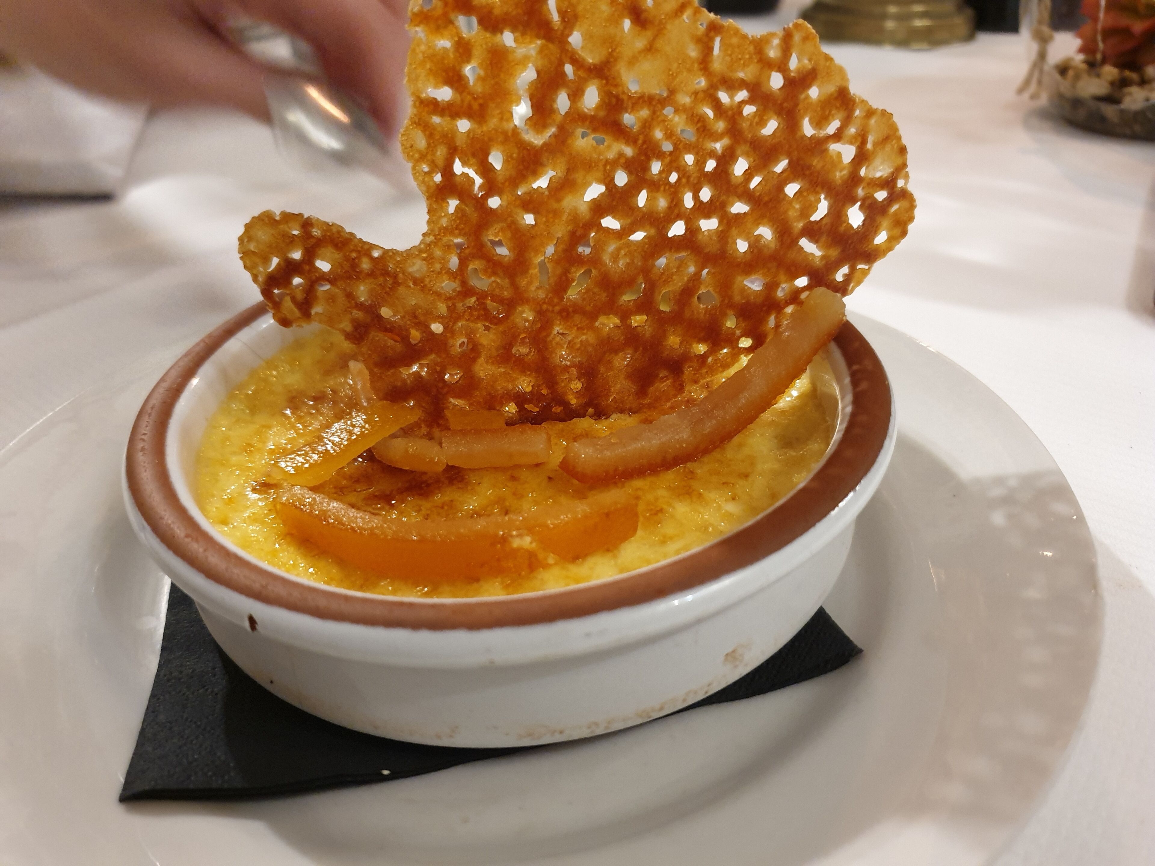 A dessert in a white bowl with a brown rim, placed on a white plate.