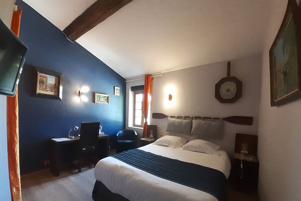 Ein Schlafzimmer mit Bett, Schreibtisch, Stuhl und einer Wanduhr.