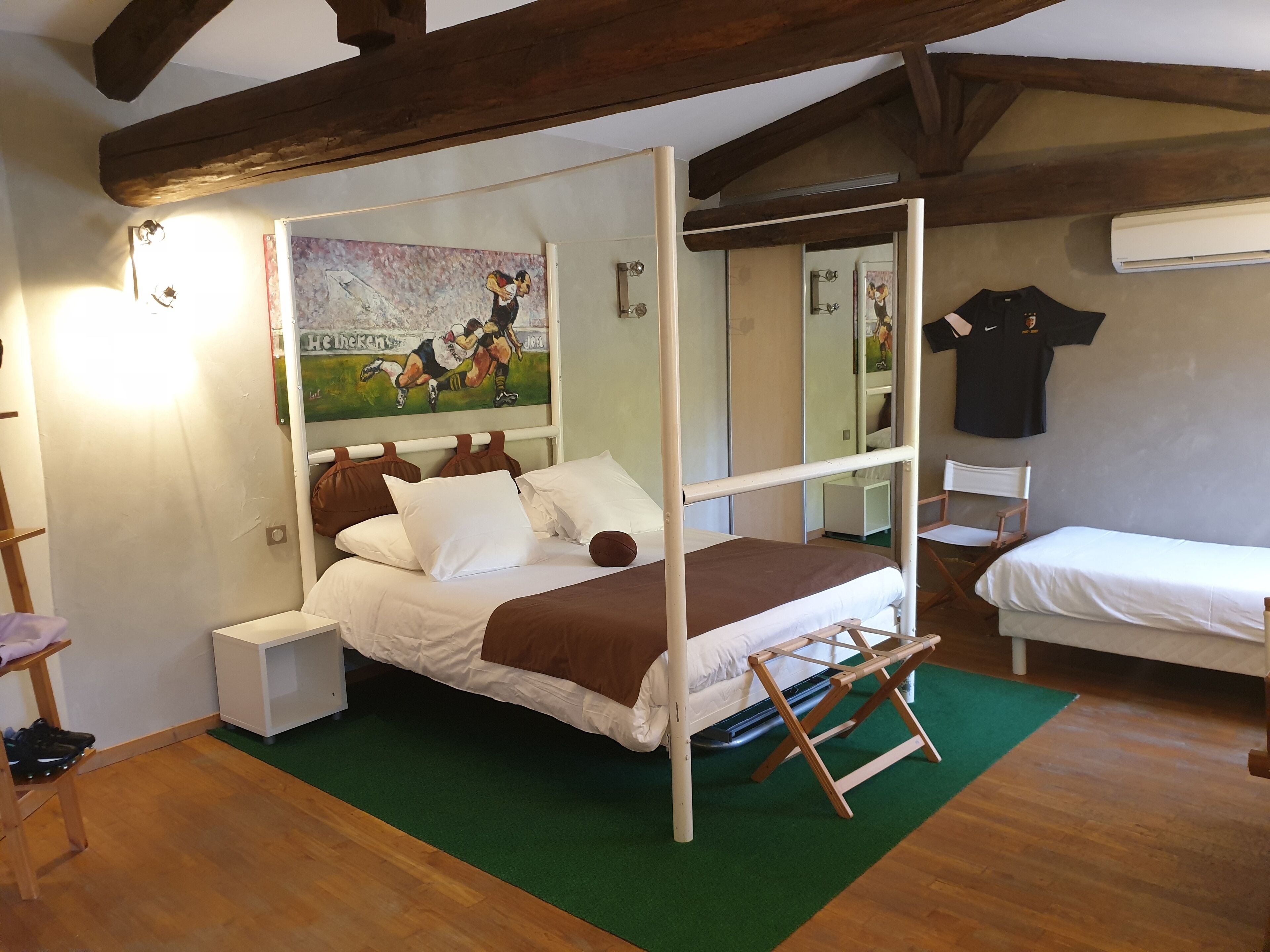 Una habitación con cama, una mesita de noche, un espejo y un equipo de aire acondicionado de pared.