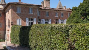 Un edificio tradicional de ladrillo con fachada simétrica, una entrada central con puerta y un pequeño jardín con sendero de grava y seto.
