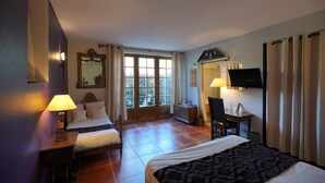 Habitación de hotel con dos camas, un escritorio, una silla, un televisor y un ventanal con cortinas.