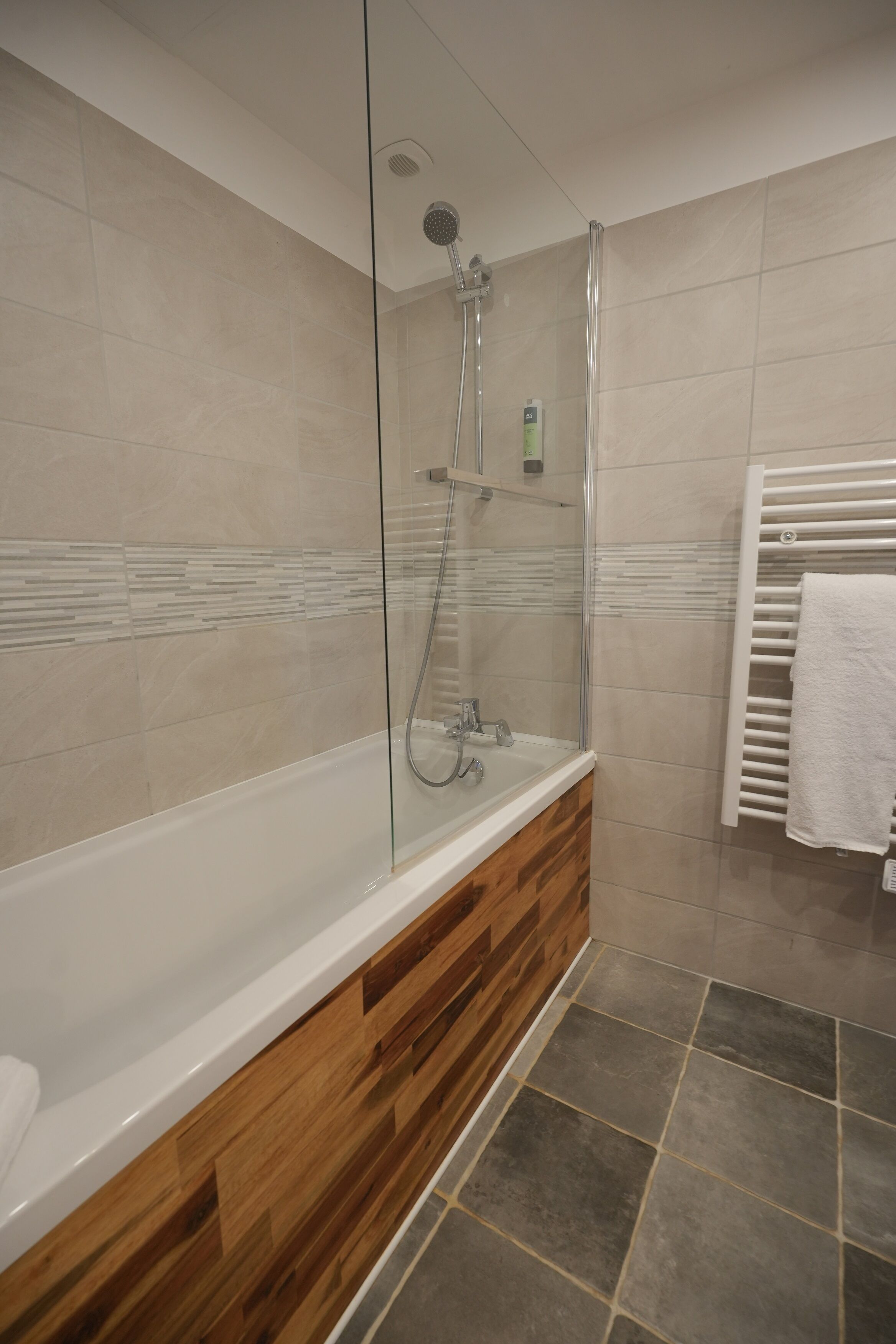 A modern bathroom with a glass-enclosed shower, a wooden vanity, and a white towel rack.