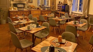 Un restaurante acogedor con mesas y sillas de madera, una zona de cocina y vista a la calle.