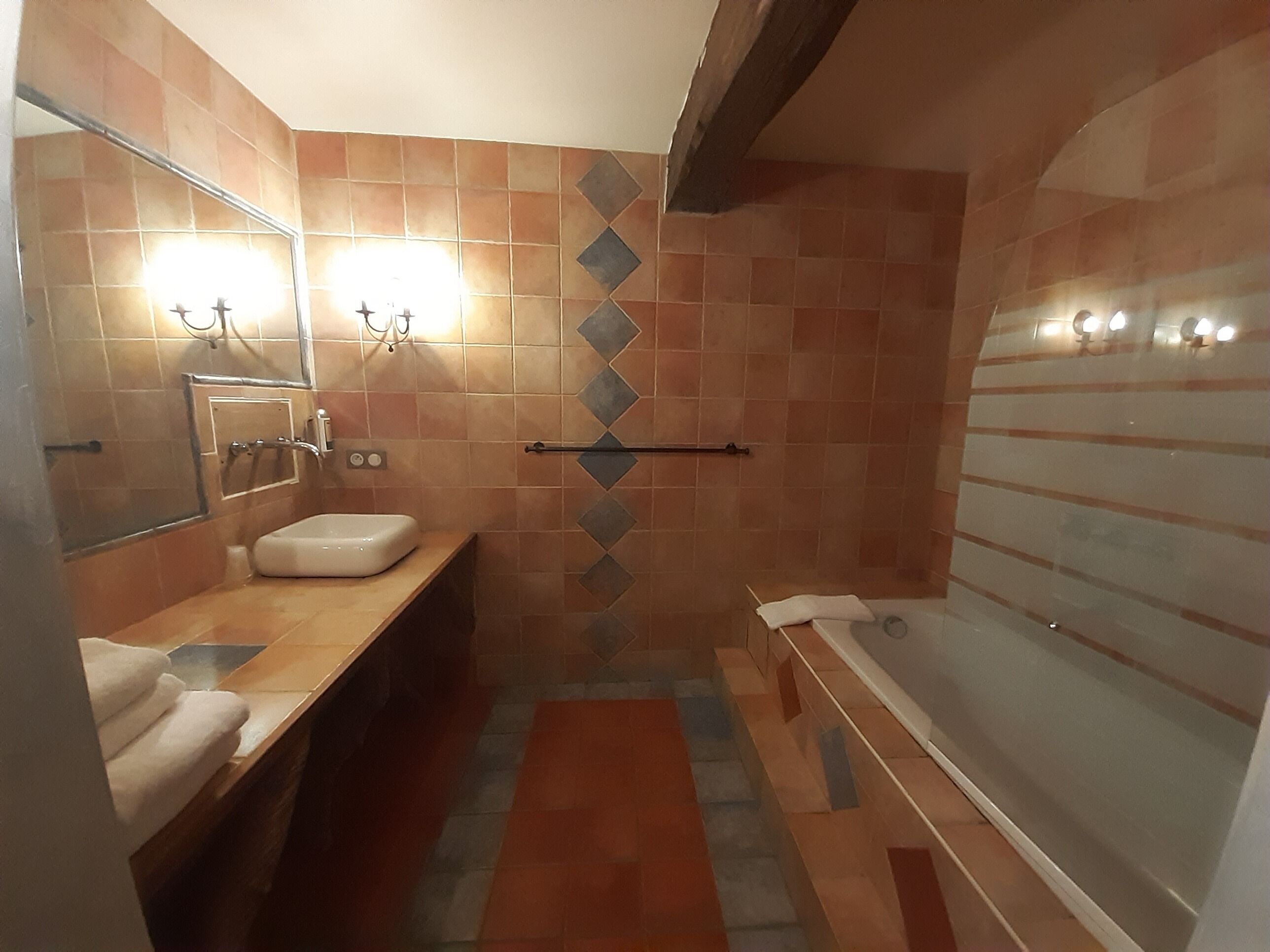 Baño con lavamanos, espejo, toallero y zona de ducha.